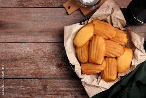 Delicious madeleine cakes on wooden table, flat lay. Space for text photo