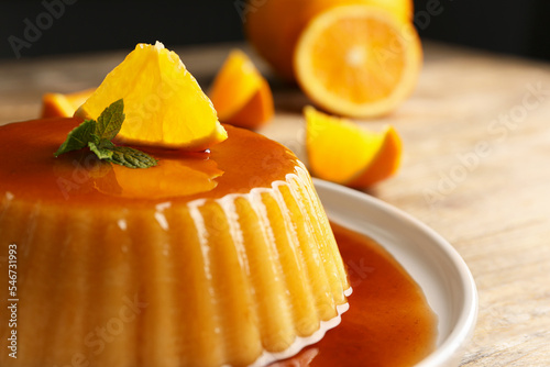 Delicious pudding with caramel, orange and mint on wooden table, closeup Fototapet