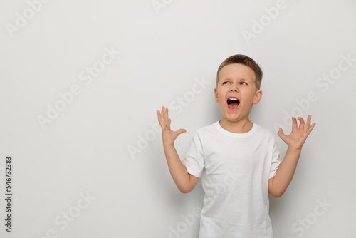 Fototapeta Angry little boy screaming on white background, space for text