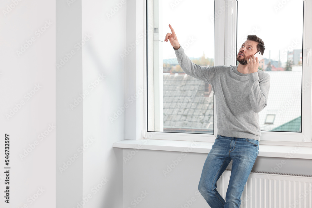 Fototapeta premium Man talking on phone near window indoors, space for text