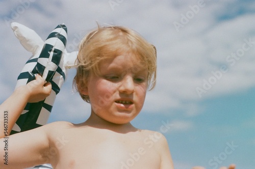 A boy on a beach with a floatable toy zebra  photo