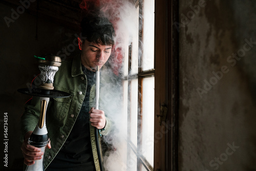 Brunet with hookah leaning on window