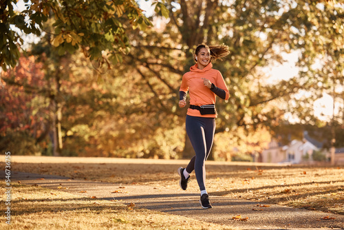 Fotografie, Tablou Full length of happy sportswoman jogging in autumn park.