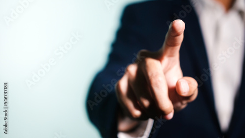Businessman in suit point finger at camera in front of white background.