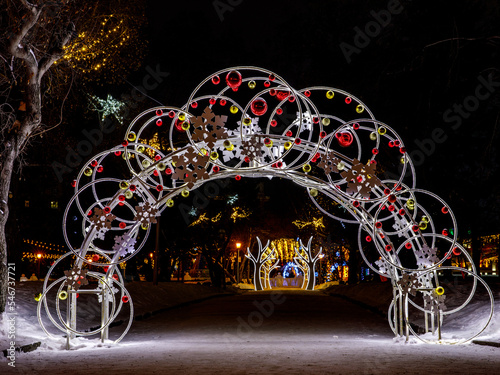 Night city Christmas decoration light arch with red and yellow new year balls and snow flakes on the central square of the city of Novosibirsk