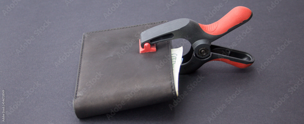 Image of a workshop clamp that keeps a wallet locked and closed where banknotes can be seen. Reference to saving and keeping your savings safe. Horizontal banner 
