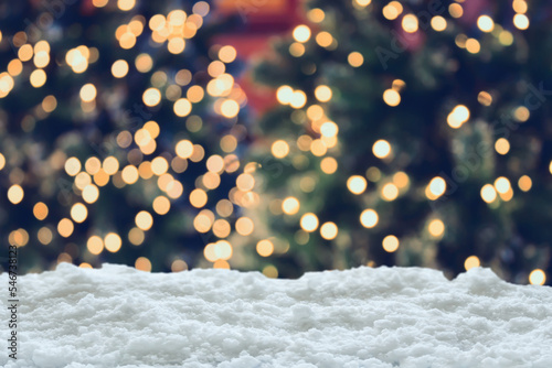 Empty white snow with blur Christmas tree with bokeh light background