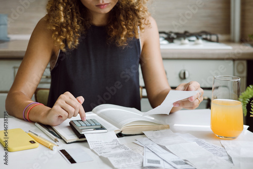 Young woman counting bills for payment on a calculator photo