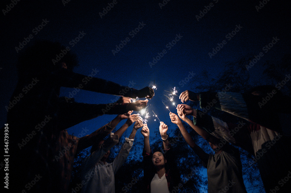 Group of young friends holding and play with fire burning sparklers