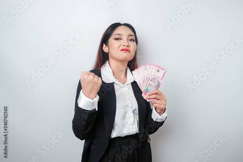 A portrait if a young businesswoman with a stack of money in Indonesian Rupiah in her hands isolated by white background