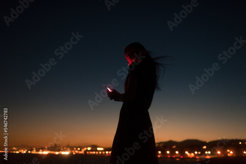 Woman using tinder during striking sunset photo