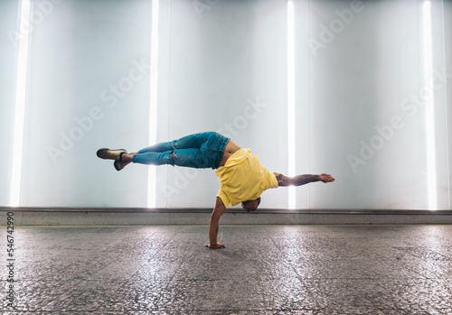 Young man doing one handed handstand and breakdancing photo