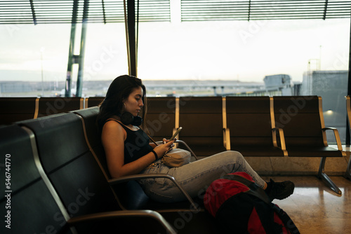 Woman at airport using mobile waiting at boarding gate photo