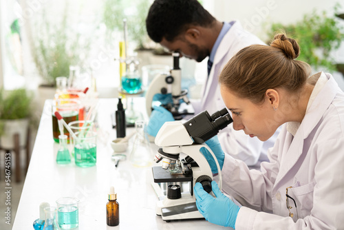 Group of Microbiologist Looking at a Lab-Grown Cultured Vegan Meat Sample in a Microscope. Medical Scientist Working on Plant-Based. medical biotechnology research laboratory using microscope.
