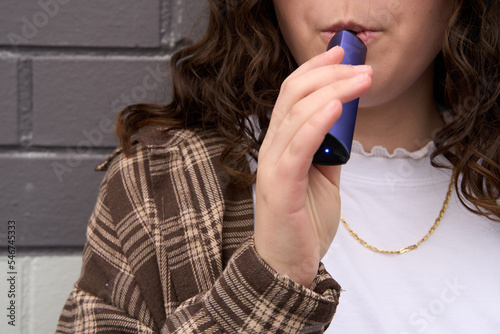 Young woman inhaling from e-cigarette 
 photo