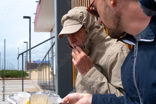 Documental style father and son consuming a delivered meal outdoors photo