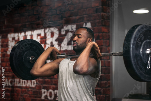 Young man training clean and jerk in gym photo