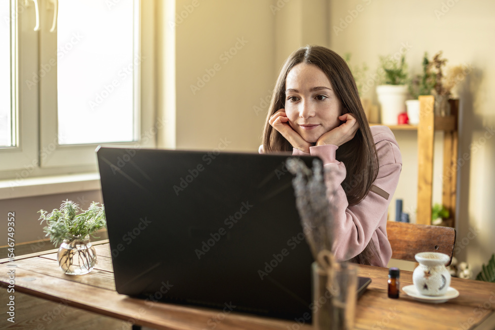 Woman is sitting in front of a computer screen in a calm pleasant atmosphere and attentively listens to video training or an online session or just communicates with a friend Woman is sitting in front of a computer screen in a calm pleasant atmosphere and attentively listens to video training or an online session or just communicates with a friend