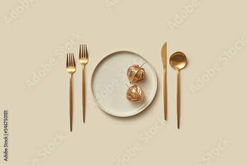 Golden cutlery and winter cherry on plate. photo
