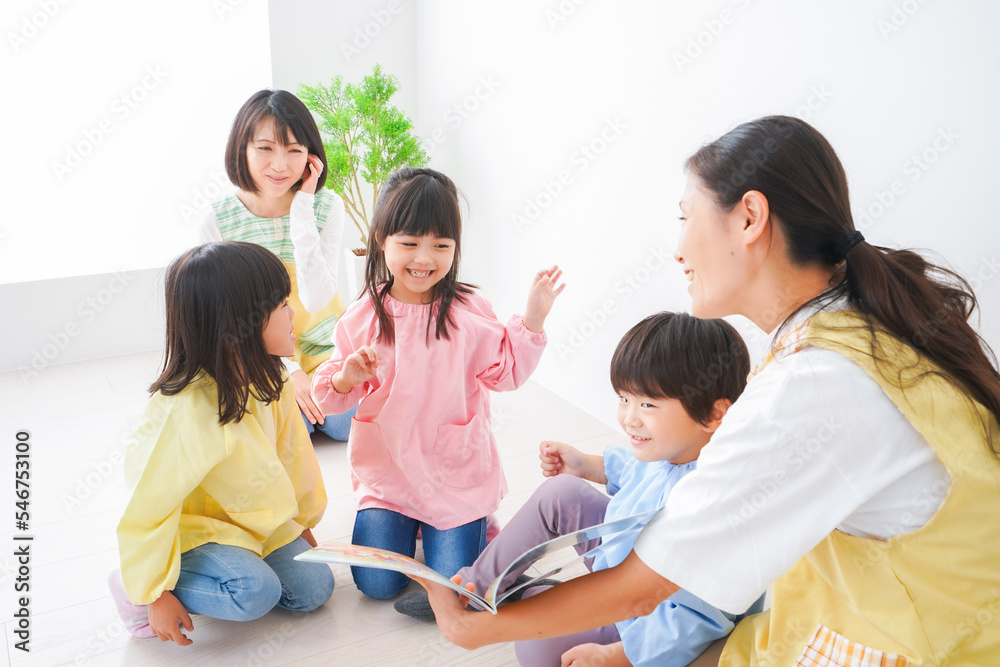 絵本の読み聞かせをする保育士と子どもたち 絵本の読み聞かせをする保育士と子どもたち