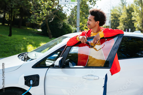 Confident man waiting for electric car to charge photo