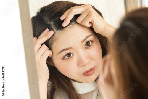鏡で頭皮を見る女性。