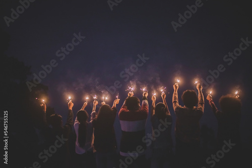 Group of young friends enjoy with burning sparkler in hands together