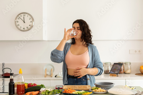 Woman drinking water preparing lunch photo