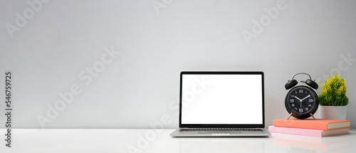 Modern workspace with laptop screen mockup, alarm clock, notebook and three decor plant and copy space for your product display on white table against the white background