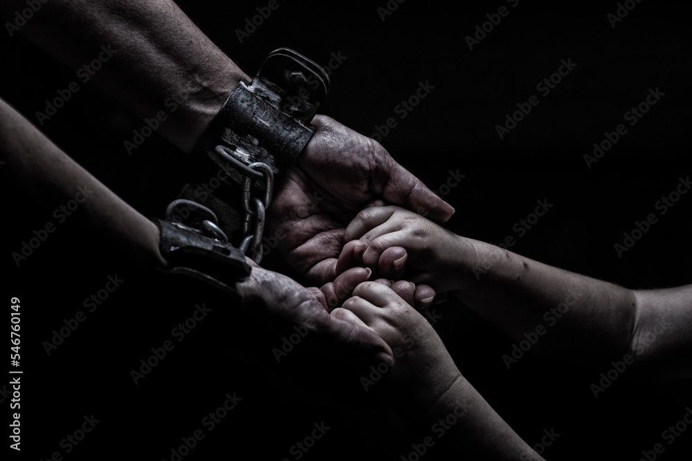 a woman in shackles holds a child by the hand on a black background Stock  Photo | Adobe Stock