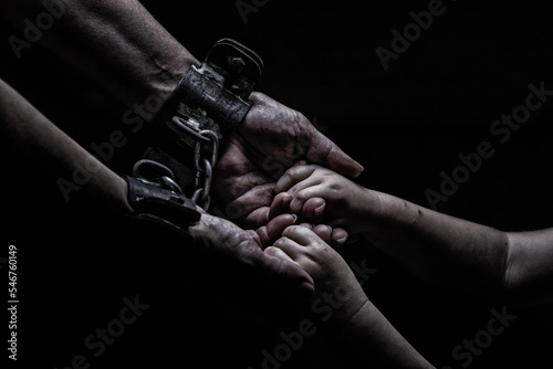 a woman in shackles holds a child by the hand on a black background Fototapet