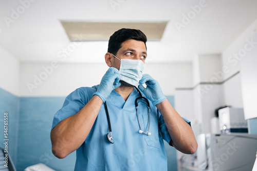 Portrait of doctor putting on protective mask photo