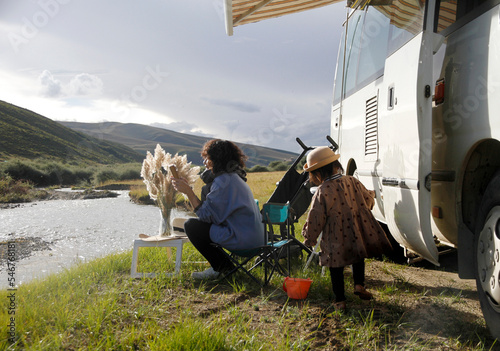 Asian mother and daughter camping by the river, plateau area

