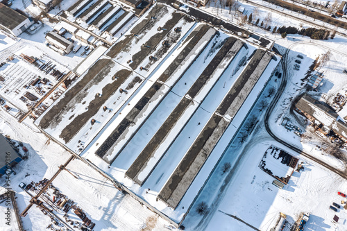 industrial area with snow-covered manufacturing buildings, warehouses, industrial equipment. aerial view at winter time.
