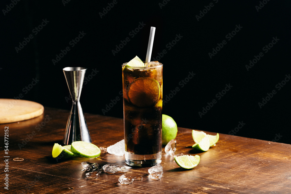 Cuba libre cocktail cold and refreshing drink for summer days on a wooden table with ice and slices of lemons Cuba libre cocktail cold and refreshing drink for summer days on a wooden table with ice and slices of lemons