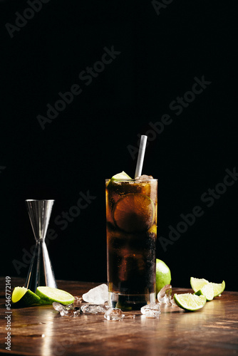 Cuba libre cocktail cold and refreshing drink for summer days on a wooden table with ice and slices of lemons