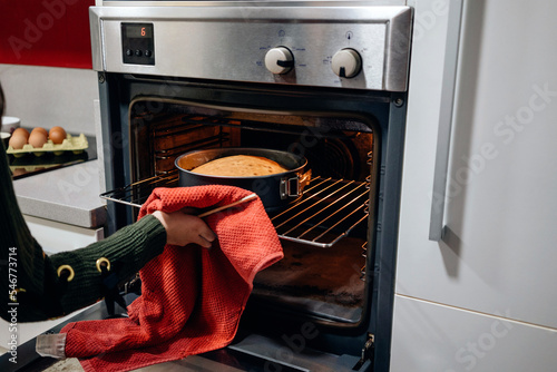 Crop girl taking out hot cake from oven