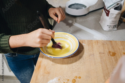 Crop girl with melted butter in bowl in kitchen