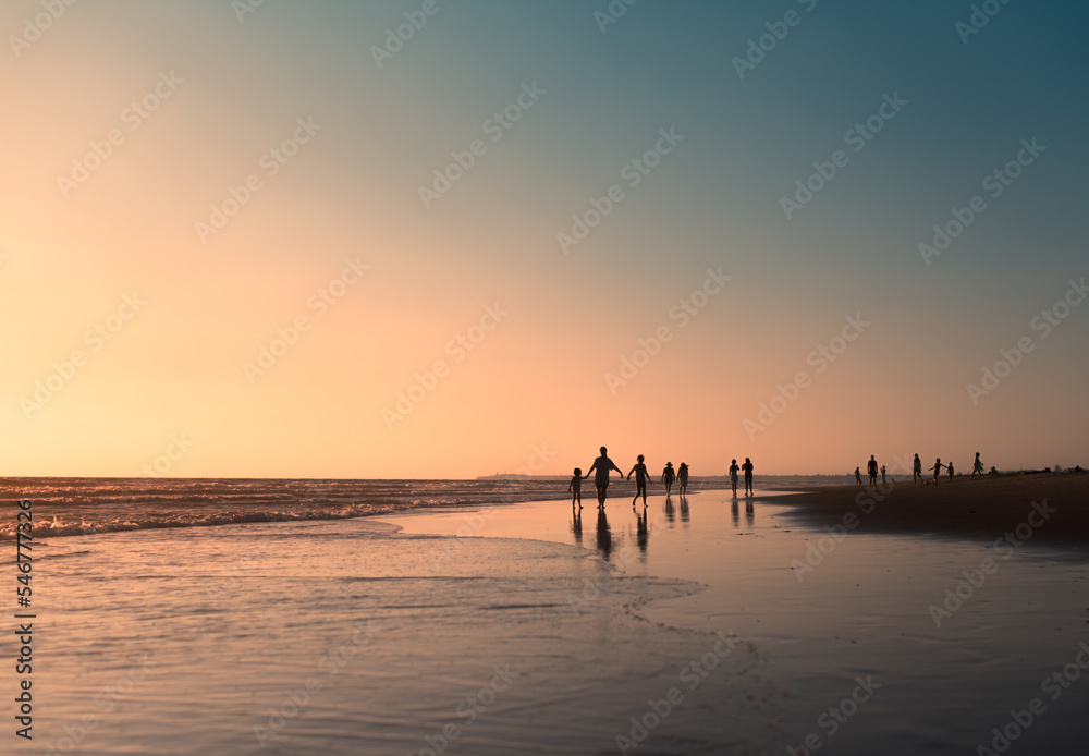 Happy walking silhouettes at sea shore during sunset Happy walking silhouettes at sea shore during sunset