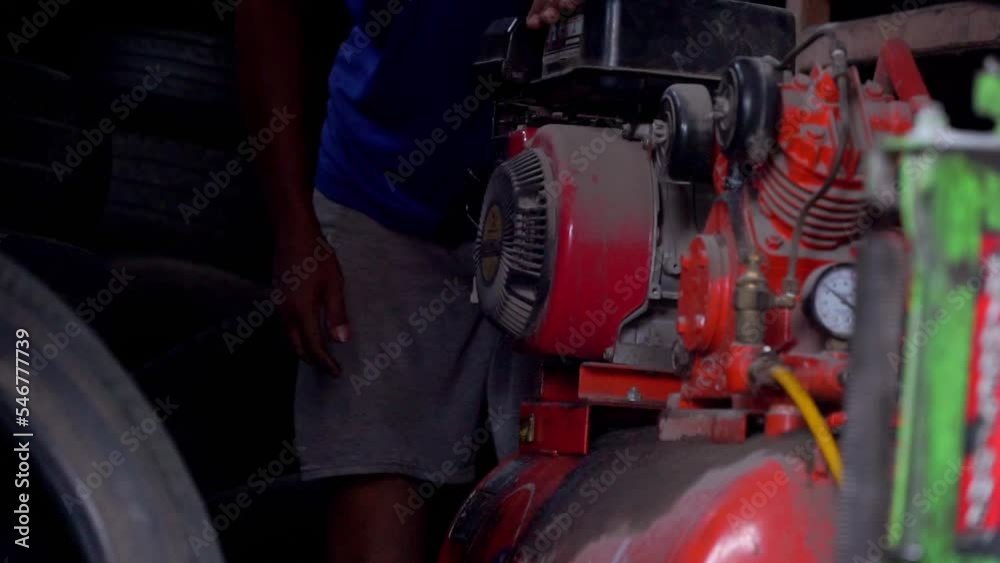 Slow motion - A man starting air compressor belt driven machine on workshop