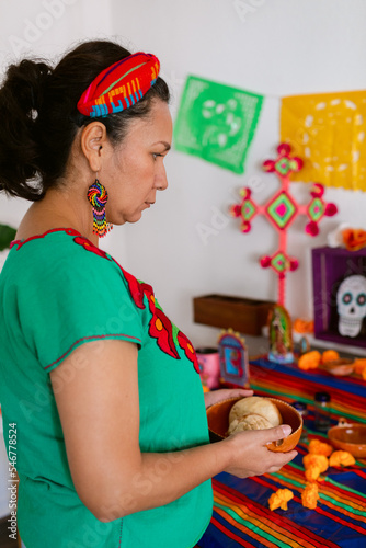 Mexican woman placing offering on altar photo