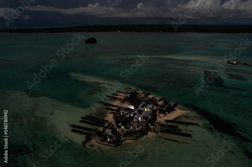 Night aerial on un-electrified Solomon islands atoll village, Pacific