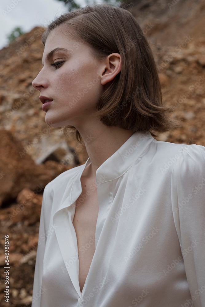 © STUDIO HAMZA/Stocksy - Woman with silk white blouse posing in nature