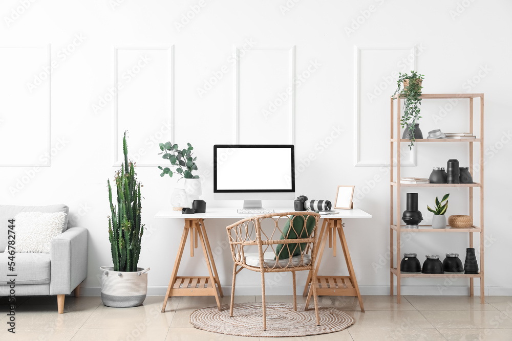 Fototapeta premium Interior of light office with photographer's workplace, shelving unit and equipment
