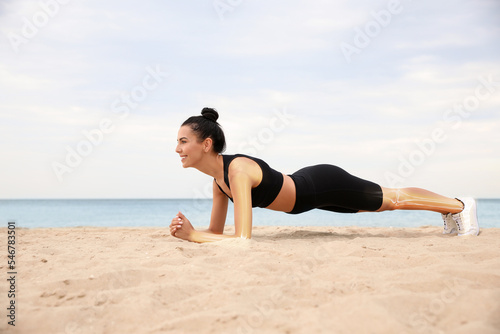 Digital composite of highlighted bones and woman doing plank exercise on beach