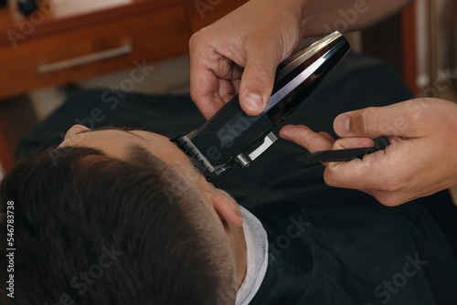 Professional hairdresser working with client in barbershop  closeup