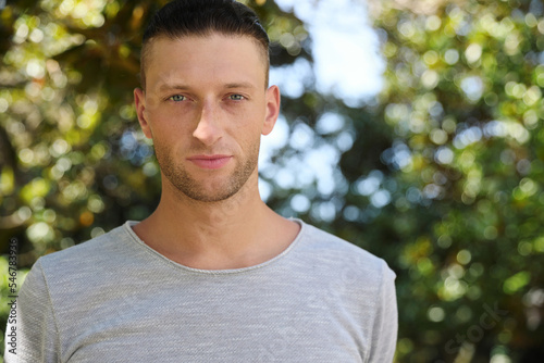 Portrait of handsome young man in park, space for text