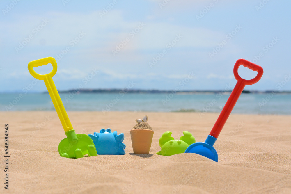 Set of colorful beach toys on sand near sea Set of colorful beach toys on sand near sea