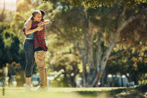 Love, relationship and interracial couple hug in park enjoying weekend, summer vacation and holiday. Affection, dating and black man hugging woman having fun, bonding and relaxing in nature together