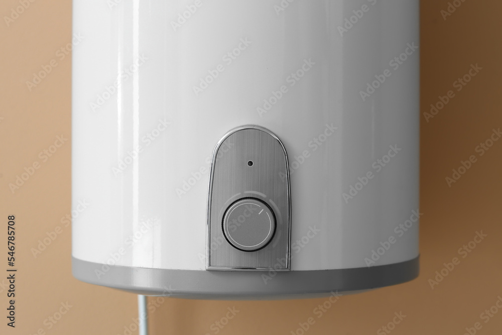 Modern electric boiler on brown wall, closeup